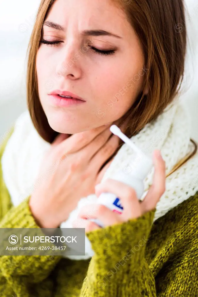 Woman using collutory spray for sorethroat.