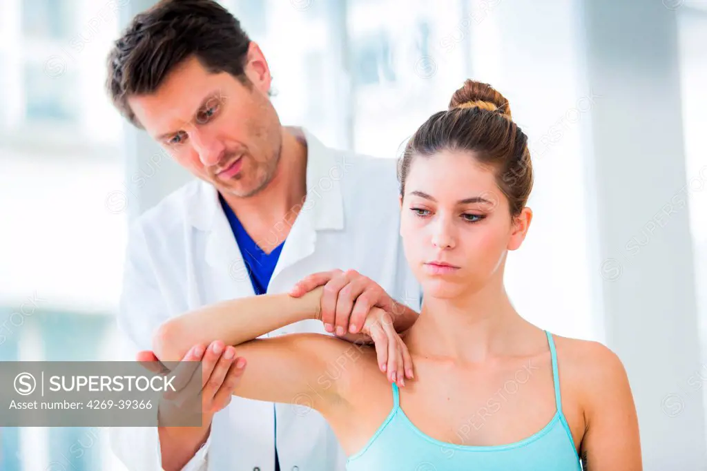 Doctor examining elbow's woman.