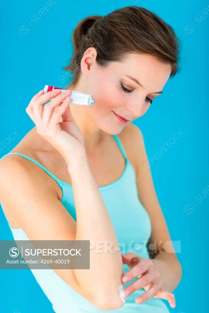Woman applying pomade on her elbow.