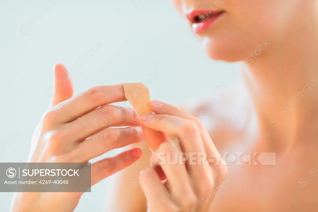 Woman putting a band-aid on her finger.