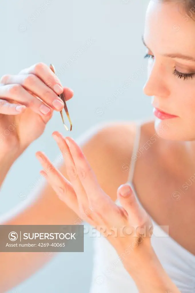 Woman removing a foreign body with a tweezer.