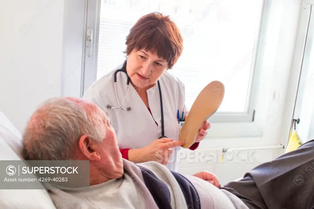 Diabetologist doctor talking to a diabetic patient about his orthopedic sole, Angouleme hospital, France.