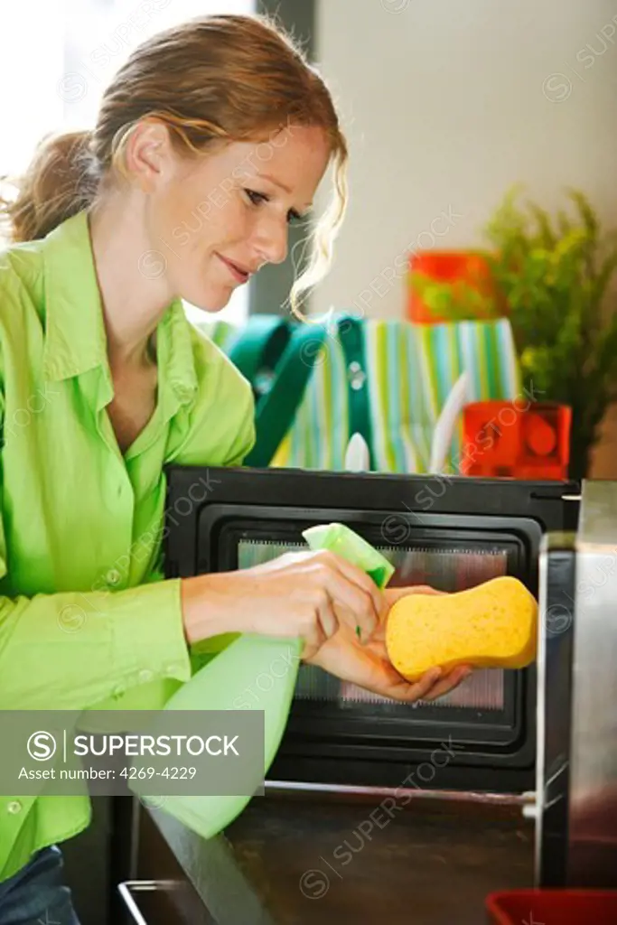 Woman cleaning microwave oven.