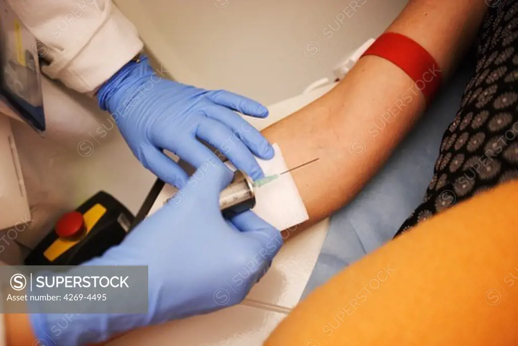 A nurse is injecting a solution of radioactive isotopes to a patient before undergoing a MRI scan (Magnetic Resonance Imaging) examination. The syringe is equiped with a lead shield to protect the technician from radiation.