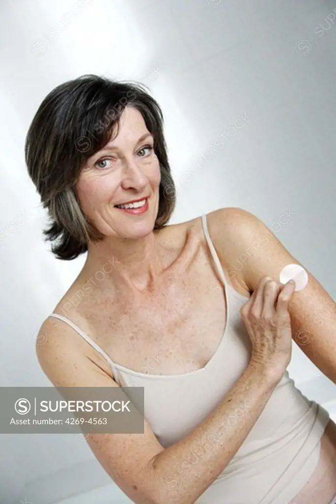 Woman using an oestrogen patch for a Hormone Replacement Therapy, in order to releive the undesirable effects of menopause.