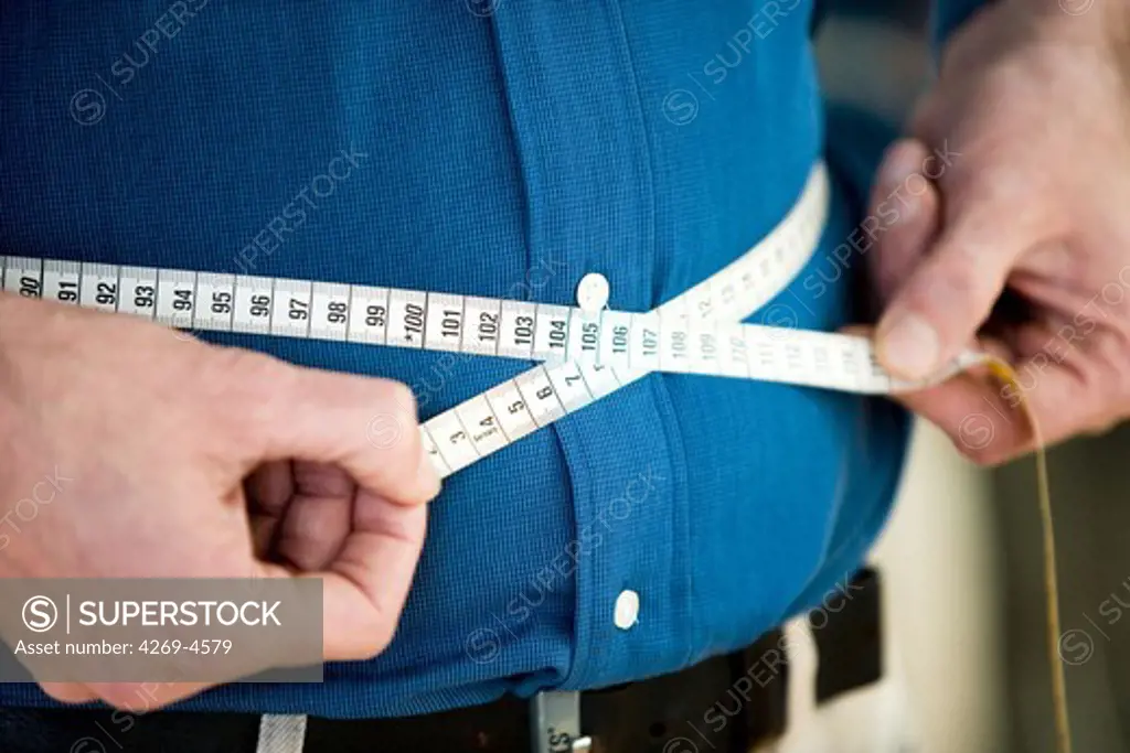 Man measuring his waist with tape measure.