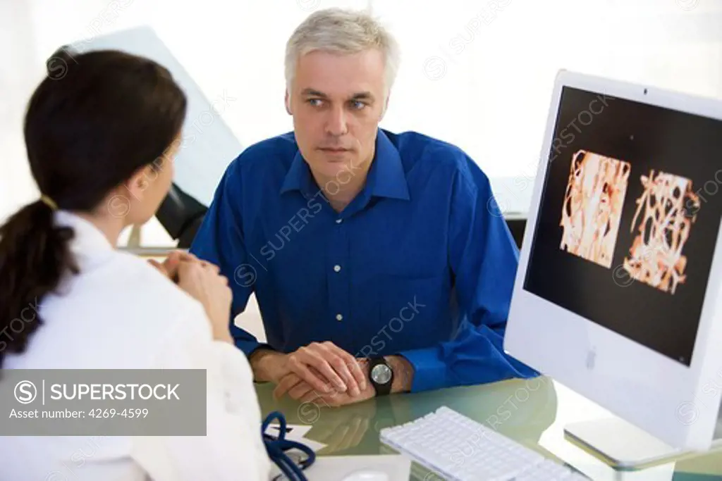 Doctor showing a patient the effect of osteoporosis on the bone structure of a vertebra.