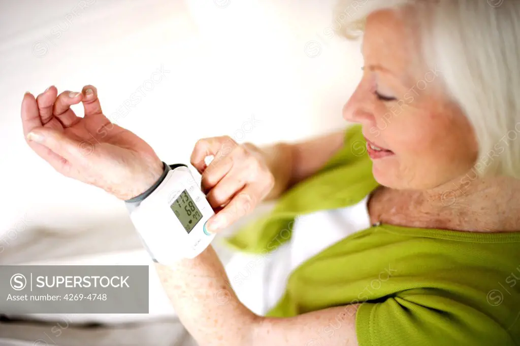 Senior woman taking her blood pressure with a portable blood pressure monitor.