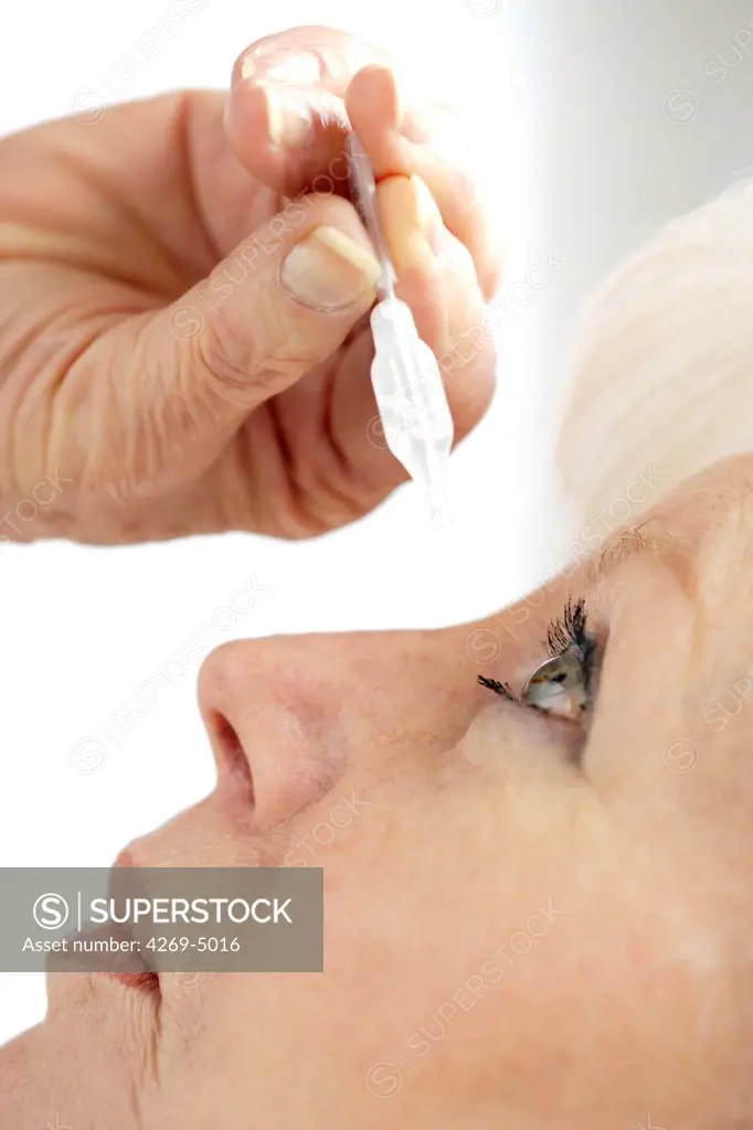 Woman applying eye-drops into her eye.