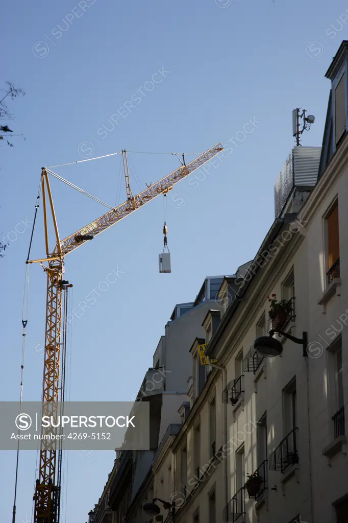 Crane setting a mobile phone relay aerial in town.