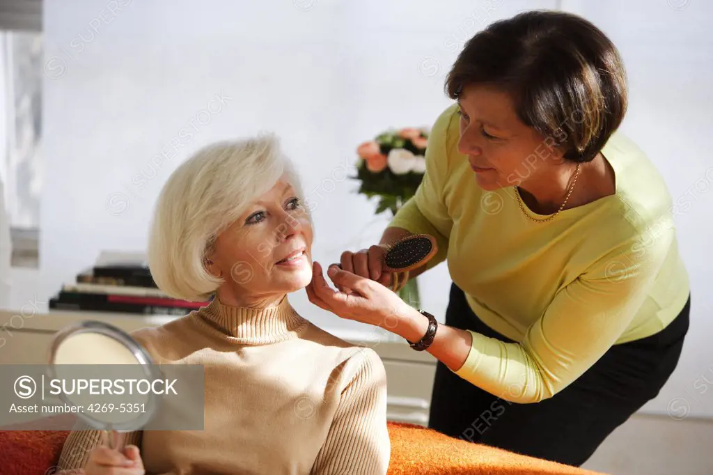 Woman doing hair of elderly woman.