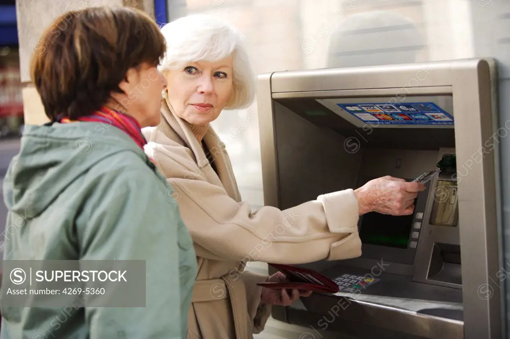 Woman and elderly woman withdrawing money from ATM.