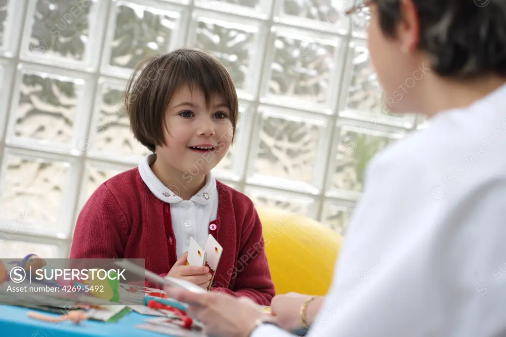 Specialist talking with a 5 years old girl during child therapy cession.