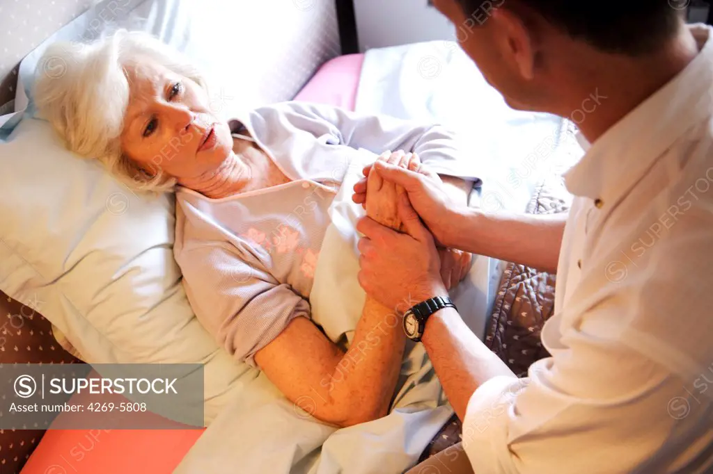 General practitioner examining elderly patient during medical consultation at home.