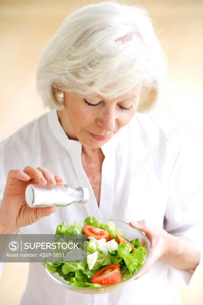 Woman adding salt on a salad.