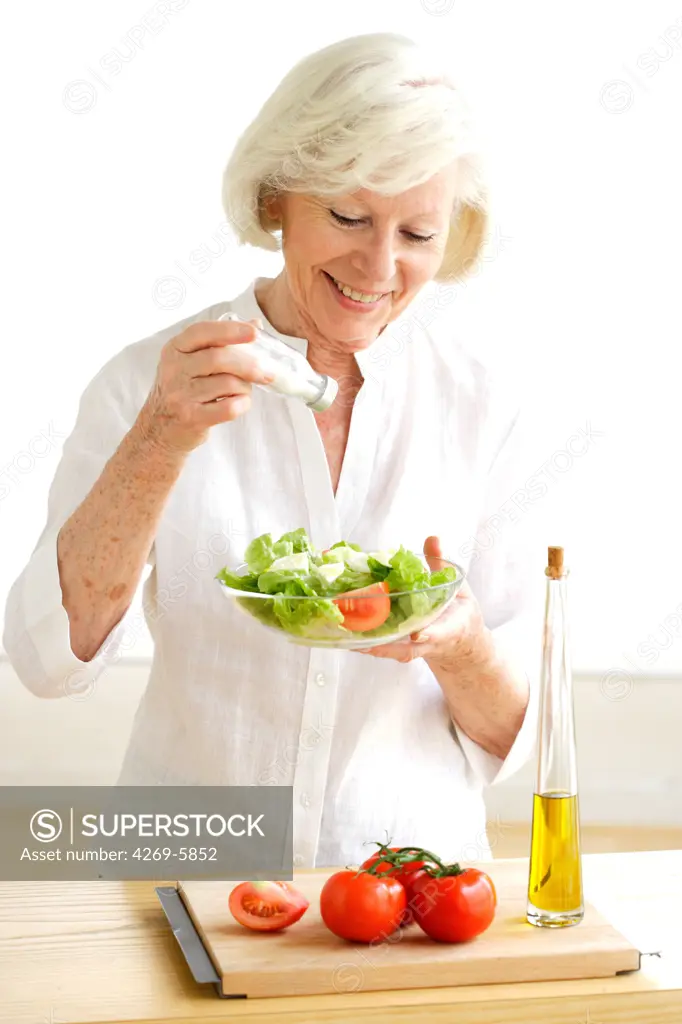 Woman adding salt on a salad.
