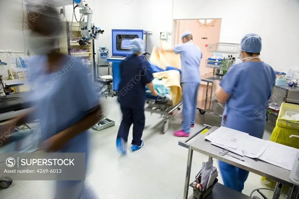 Surgical staff bringing patient in operating room.