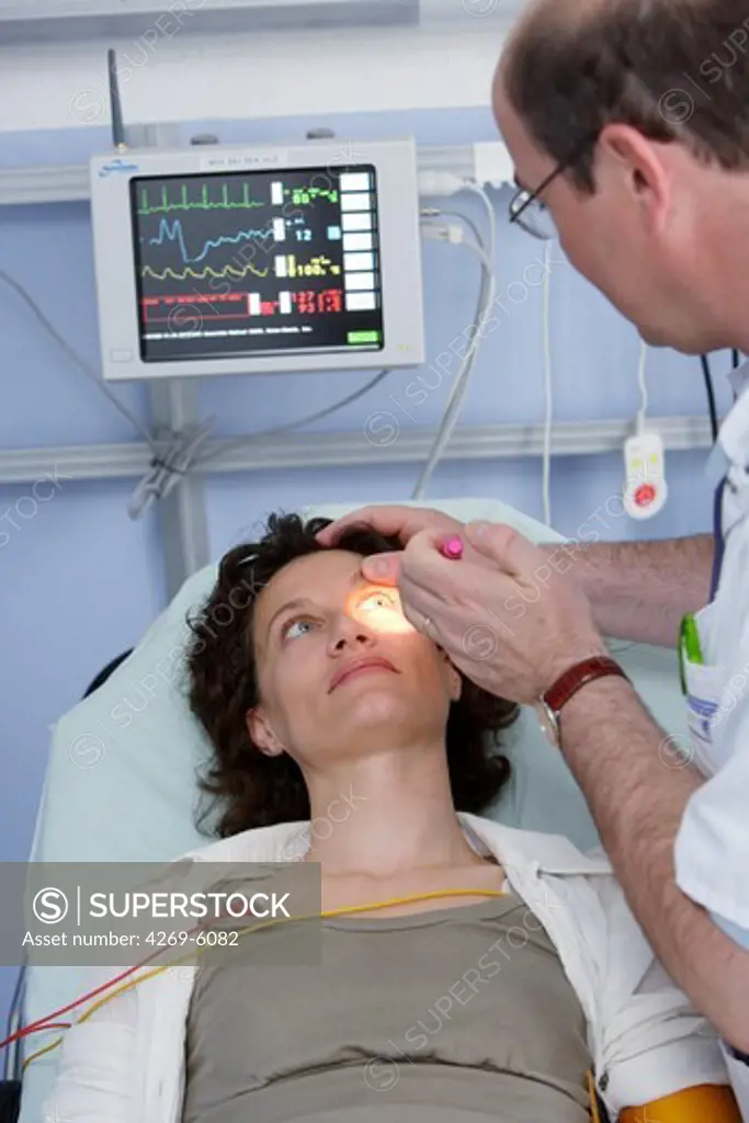 Assessing pupil dilation : hospital doctor performing neurological examination of a patient at emergency department.