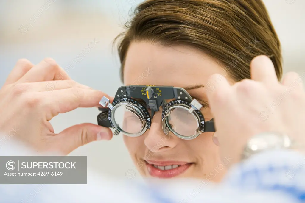 The optician tries different ophthalmic lenses for prescription glasses.