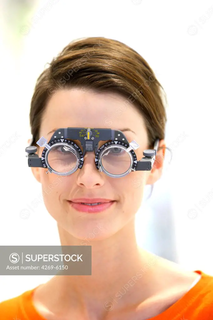 The optician tries different ophthalmic lenses for prescription glasses.