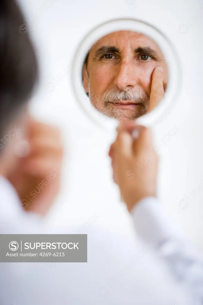 Man inspecting his face in a mirror.