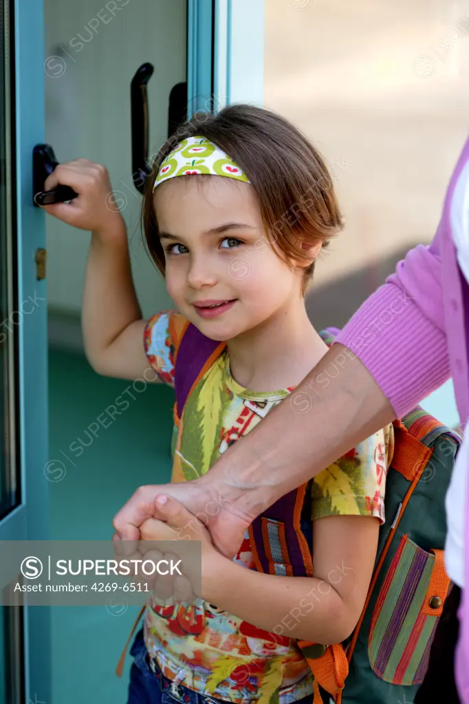 6 years old girl in front of school door with her mother.