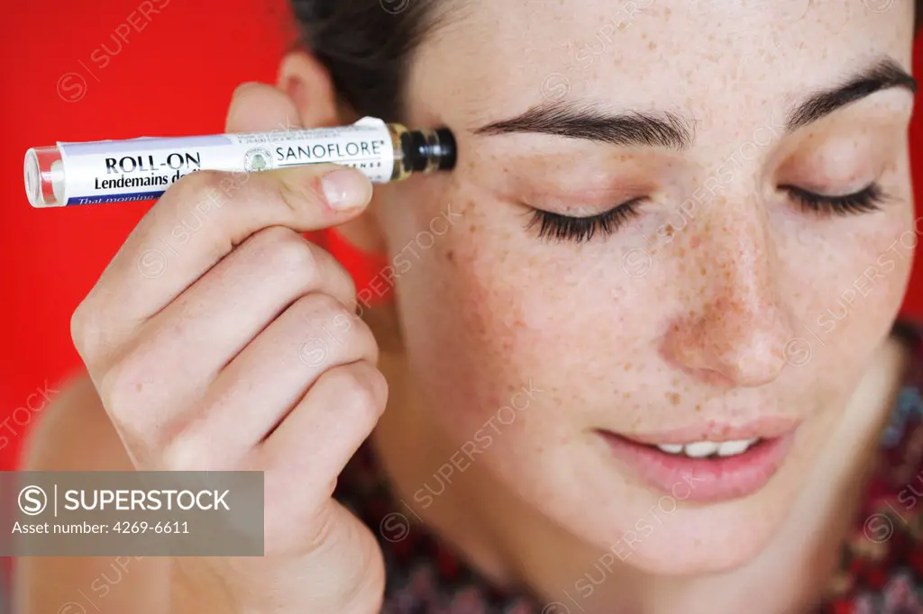 Woman applying essential oils on her temples with an applicator.
