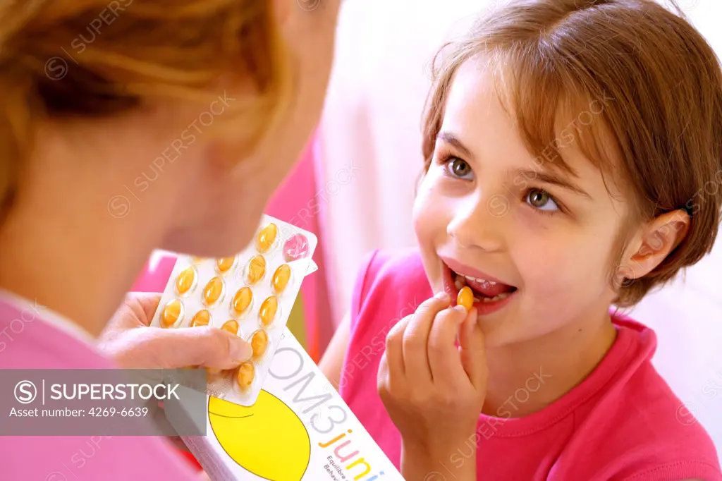 Young girl taking caspules of food supplement.