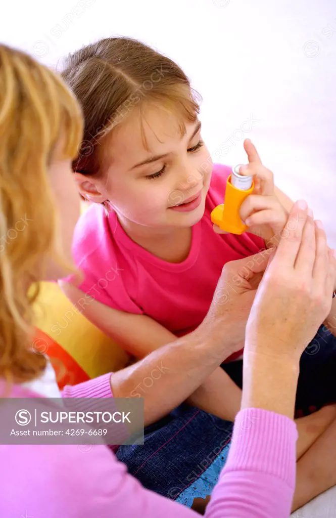 Child using an aerosol inhaler that contains bronchodilator for the treatment of asthma. The inhaler dilates lungs airways to improve breathing.