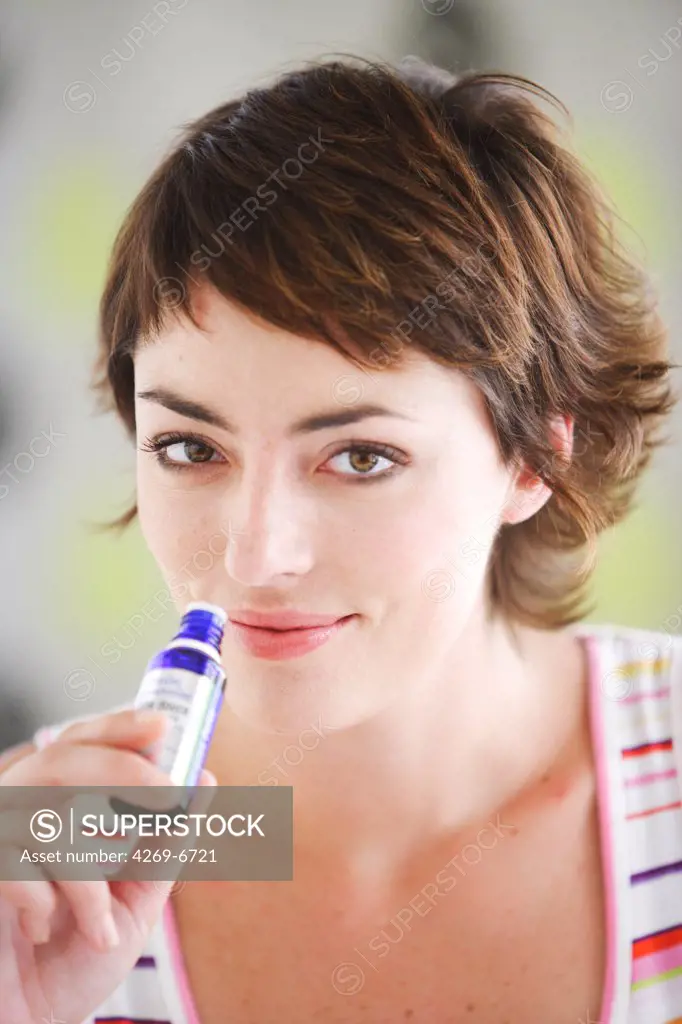 Woman smelling a bottle of essential oil.