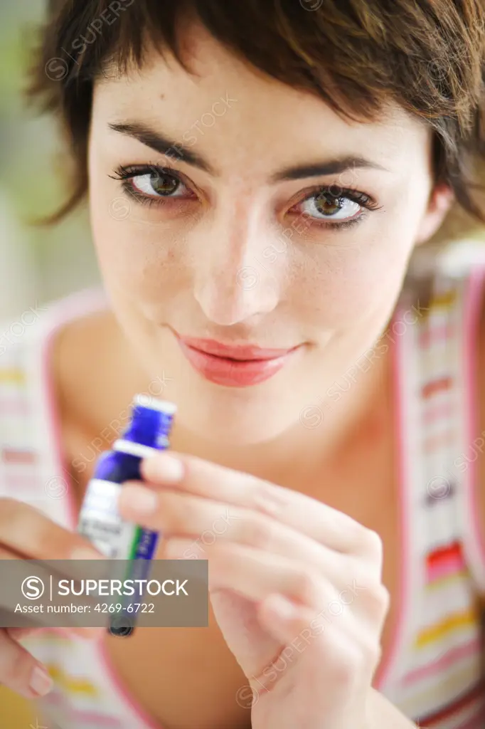 Woman smelling a bottle of essential oil.