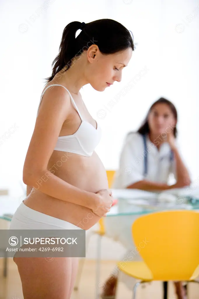 Pregnancy monitoring : doctor weighing a pregnant woman during medical consultation.