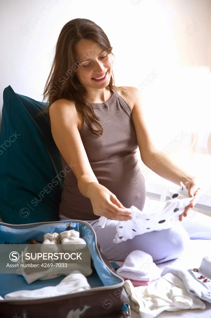 Pregnant woman packing her bag before going to maternity.