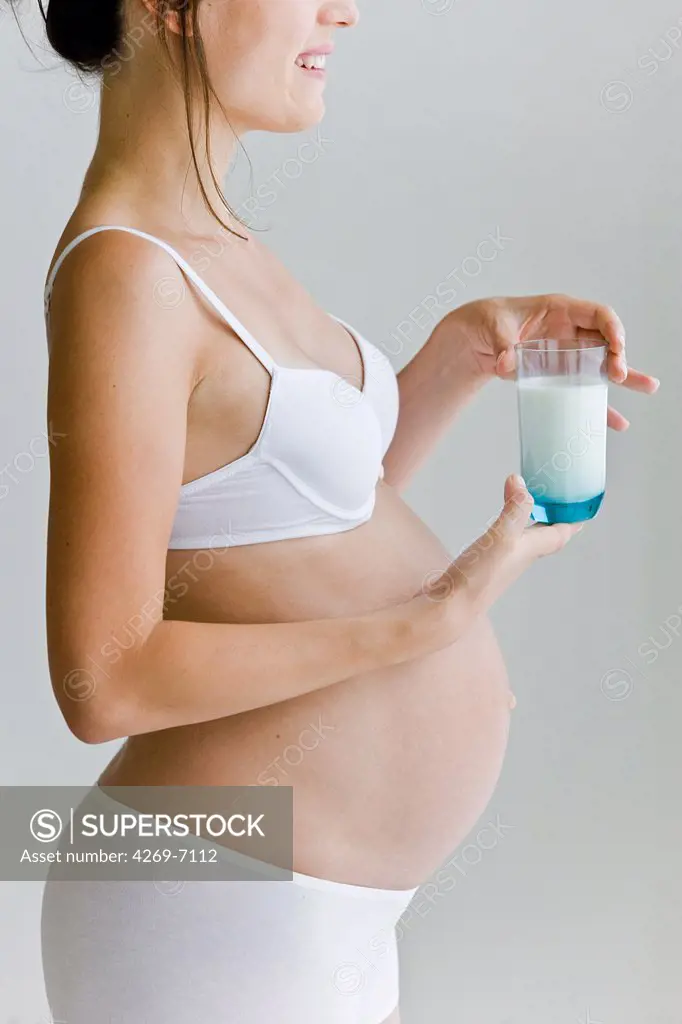 Pregnant woman drinking a glass of milk.