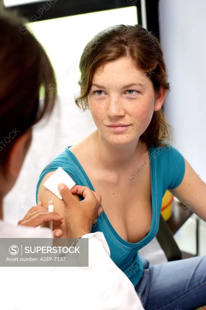 Female teenager receiving a vaccination from a doctor during medical consultation.