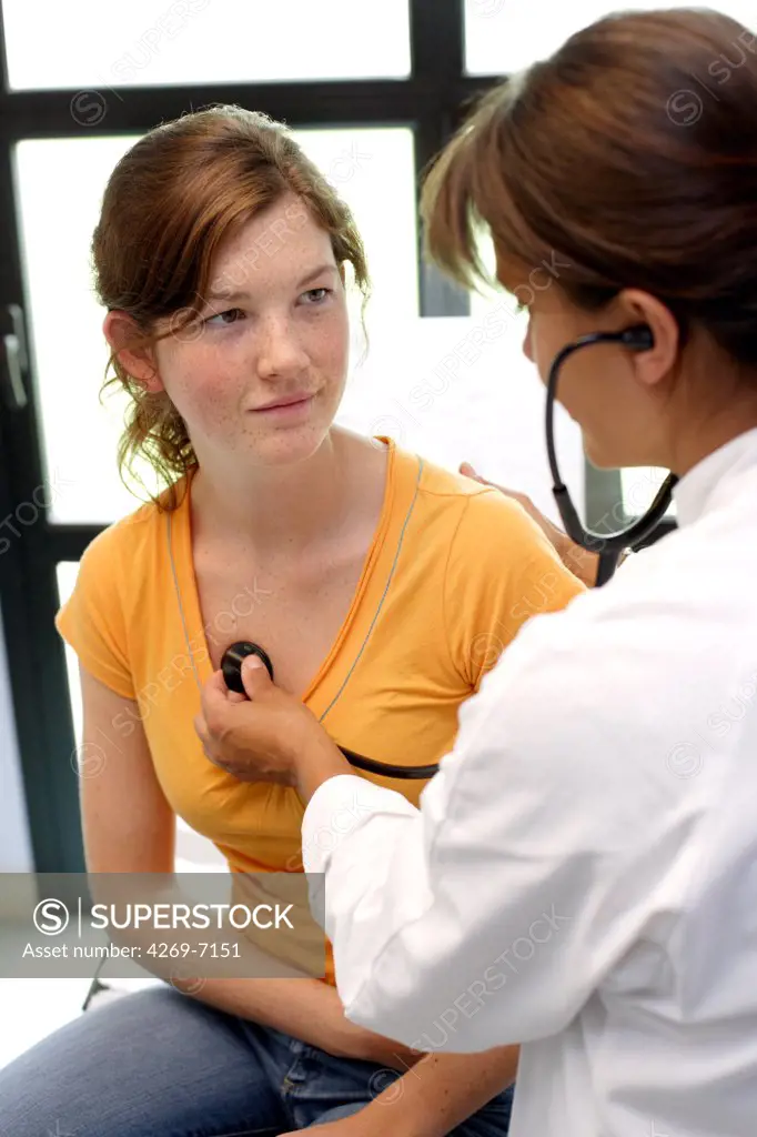 Doctor examining chest of a female teenager with a stethoscope.