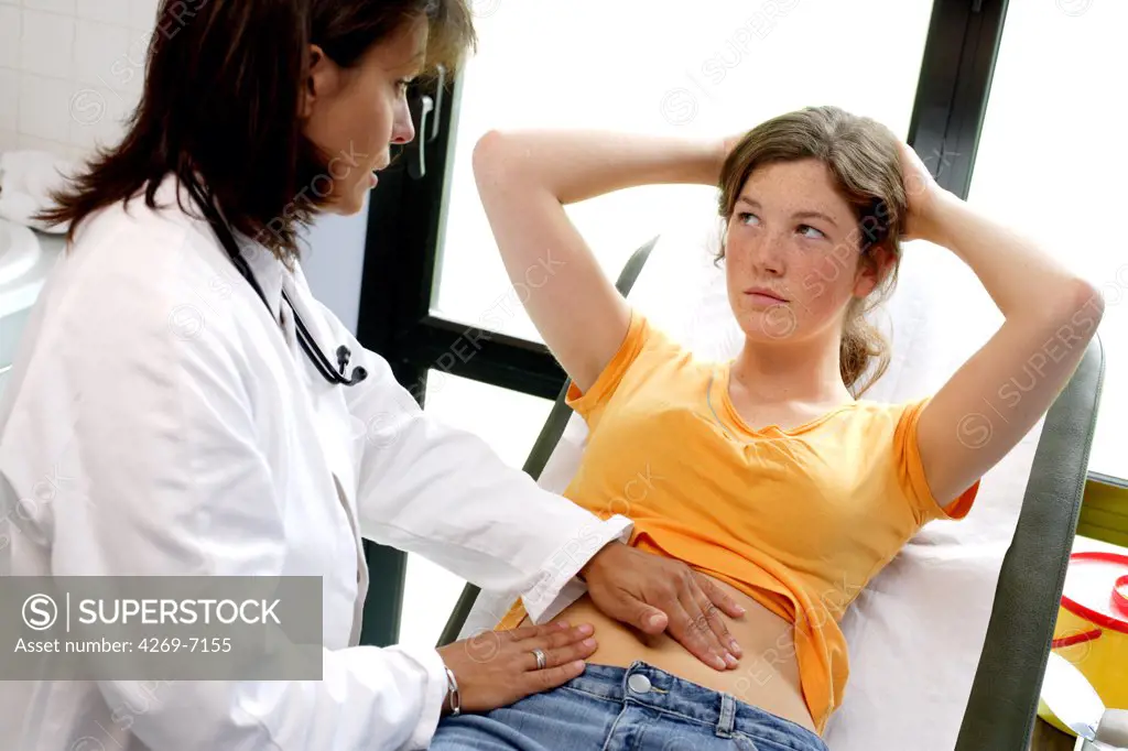 Doctor examining the abdomen of a female teenager by palpation.