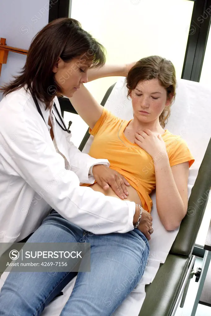 Doctor examining the abdomen of a female teenager by palpation.