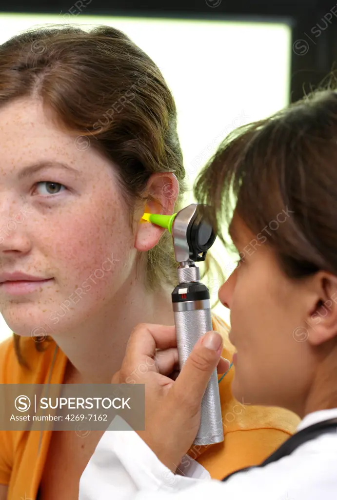 Doctor examining the ears of a patient with an otoscope.