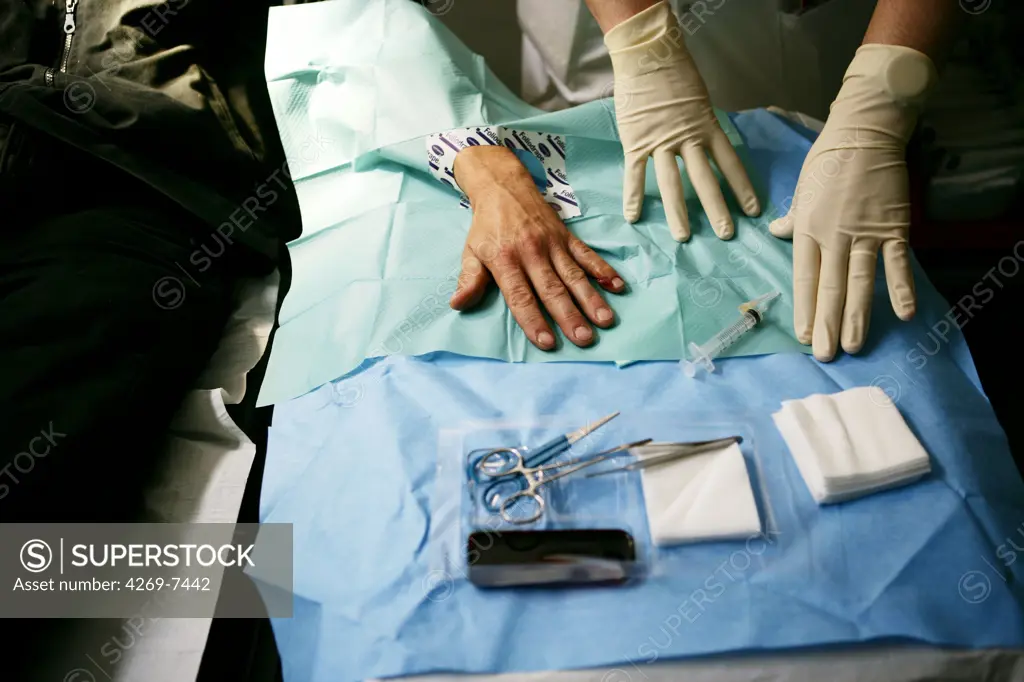 Doctor stitching up the hand of a patient. Emergency Department, Lariboisière Hospital, Paris, France.