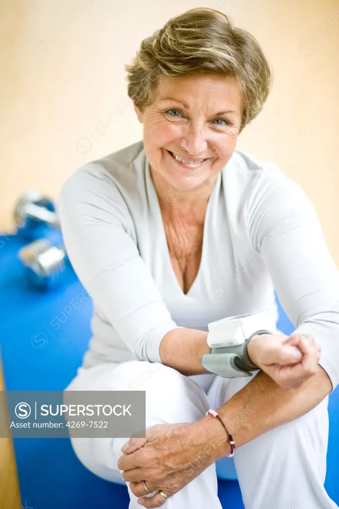 Senior woman taking her blood pressure with a portable blood pressure monitor.