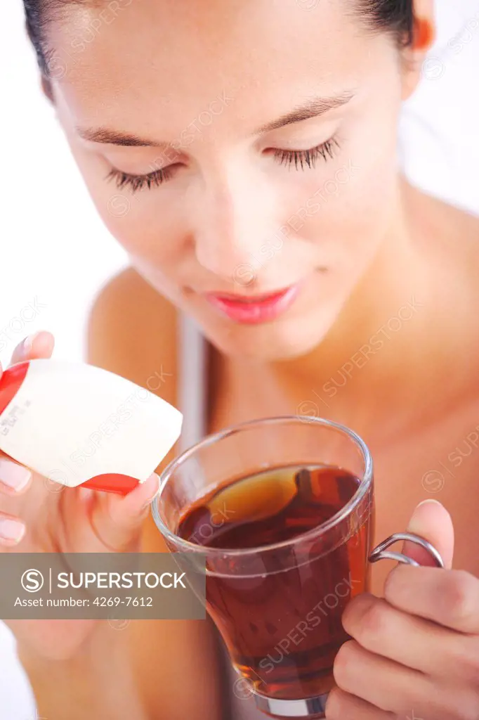 Woman adding artificial sweetener to infusion.