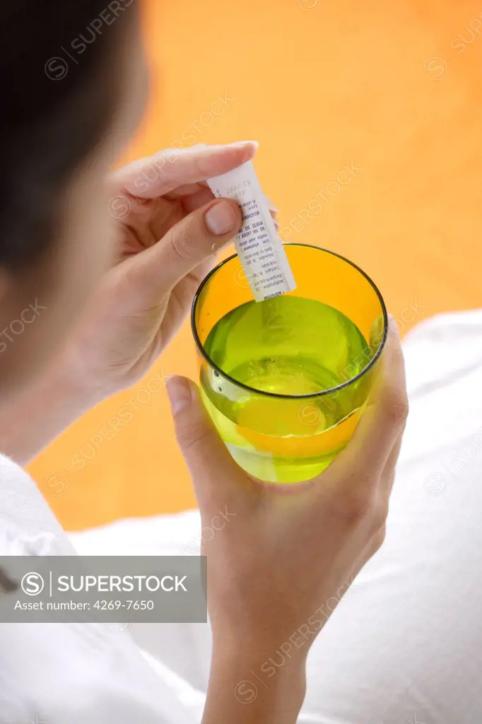 Woman dissolving powder medicine in a glass of water.