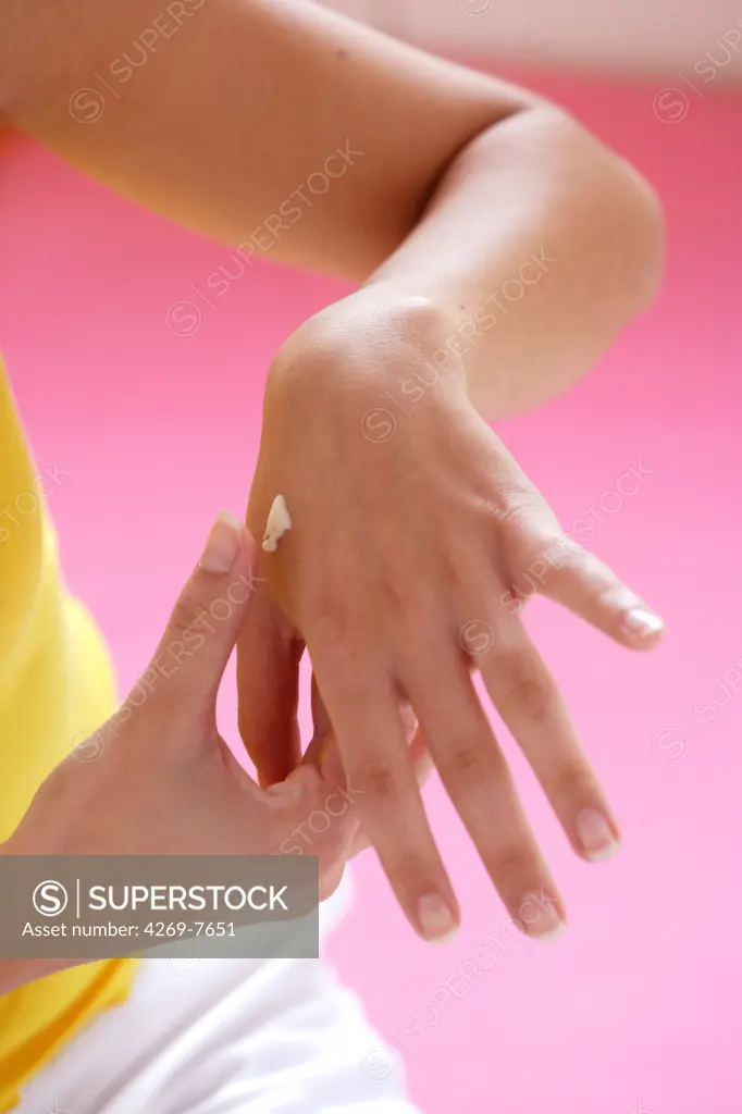 Woman applying moisturizing cream on her hands.