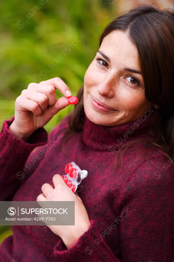 Woman taking lozenge for sorethroat.