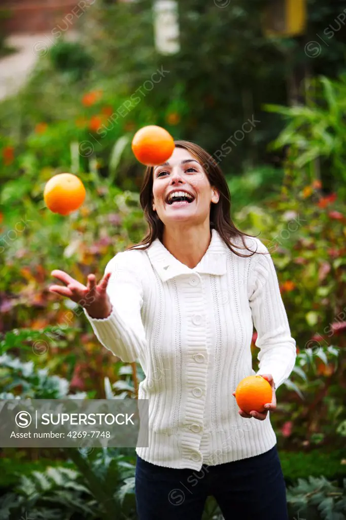 Woman juggling with oranges.