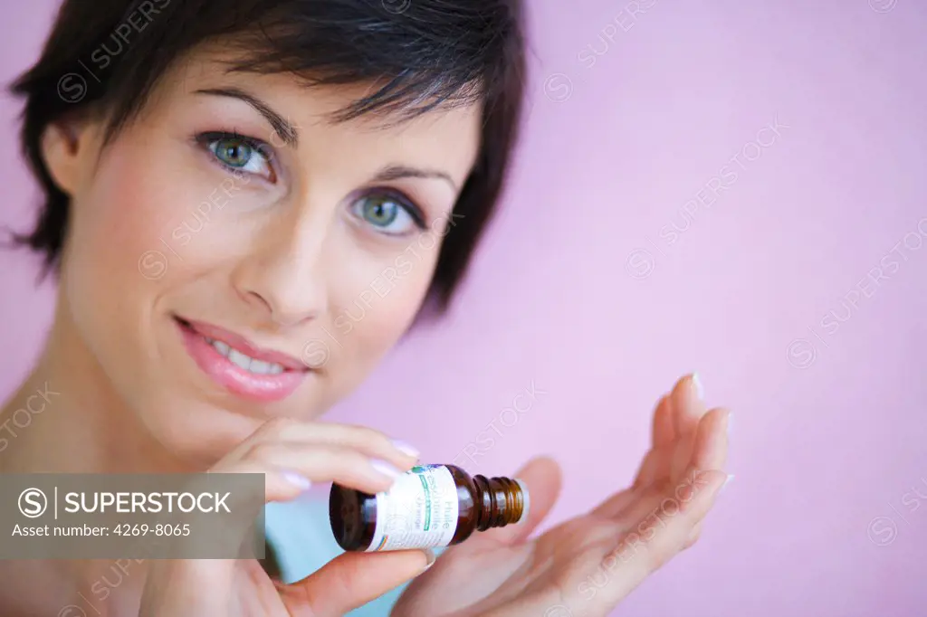 Woman applying essential oil on her skin.