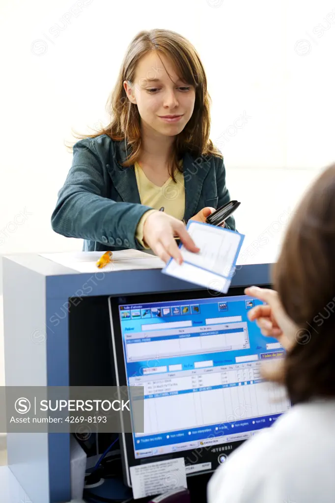 Woman giving documents at reception desk.