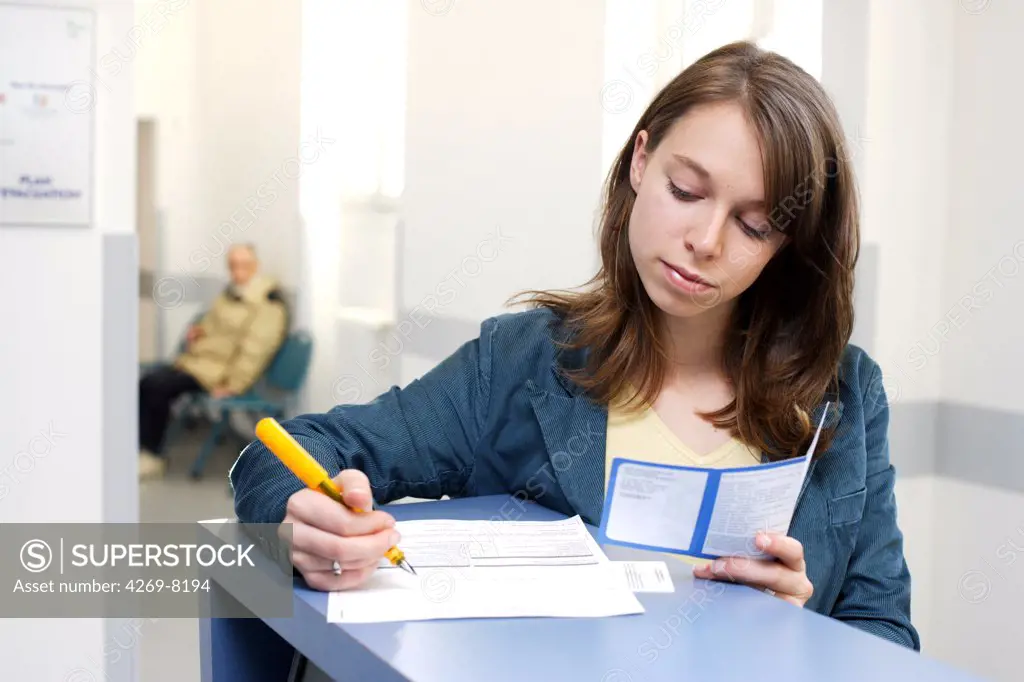 Woman filling form at reception desk.