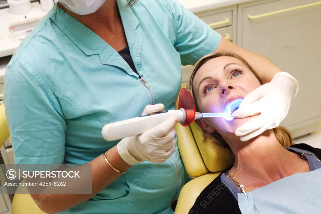 Dentist using ultra violet light to activate teeth withening solution.